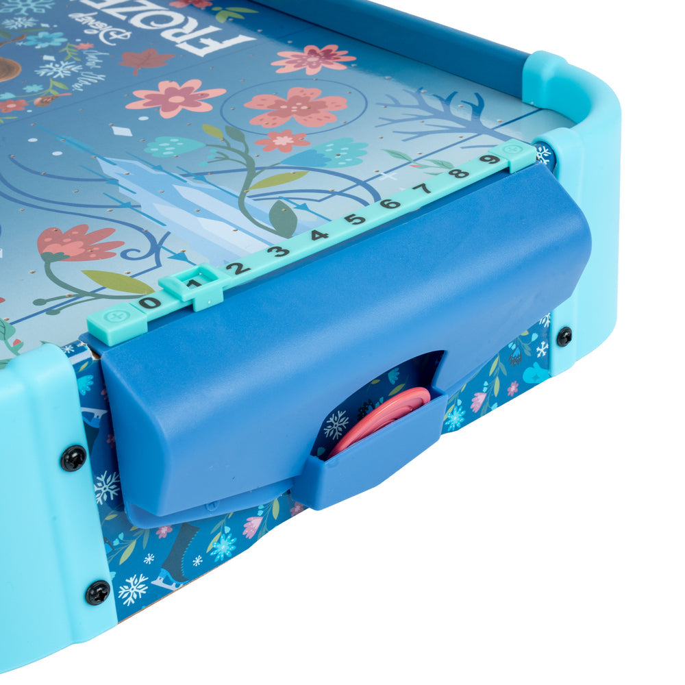 Close-up of a Frozen-themed children's activity board or game, showing a blue plastic control panel, turquoise side frame, floral printed top surface, and a pink circular component on a white background.