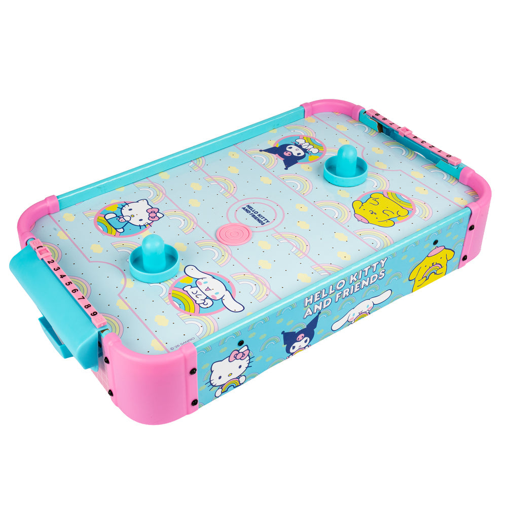 A Hello Kitty and Friends air hockey game featuring a light blue tabletop with pastel illustrations of Hello Kitty, Cinnamoroll, Kuromi, and Yuru Yuri, surrounded by pink plastic sides and turquoise handles.